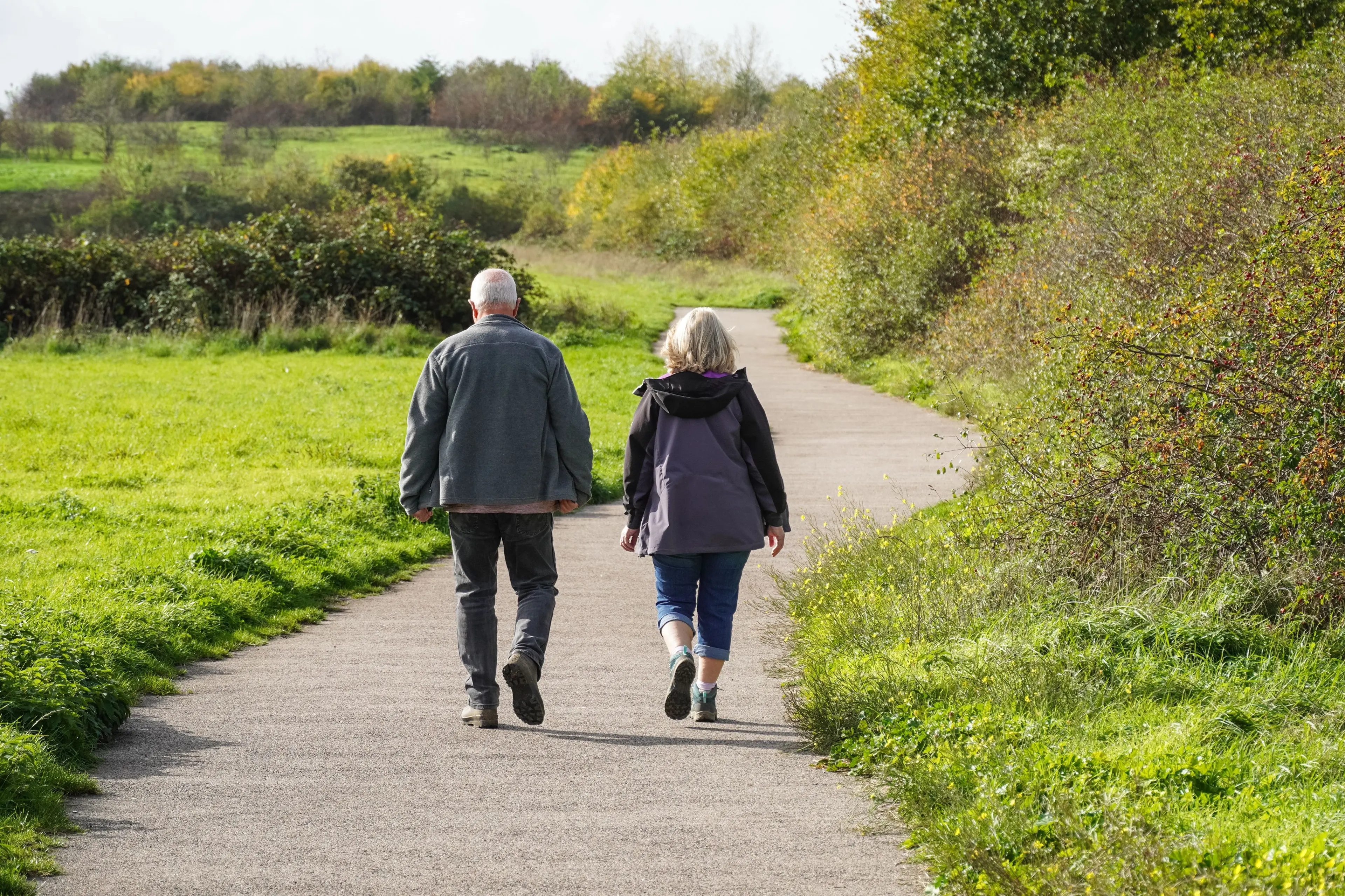 elderly couple walking down a gravel path
