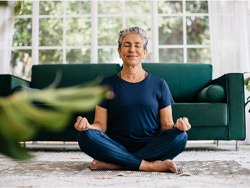 An eldery woman meditating on a rug