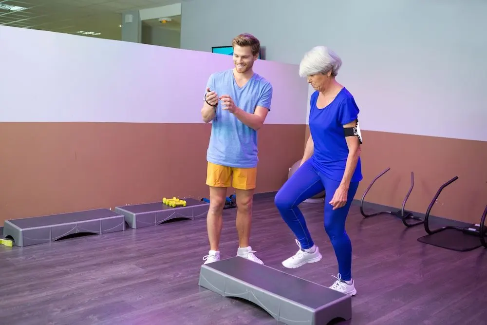 A young man training an older woman in a gym